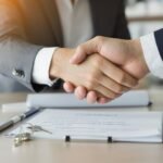 Handshake over house keys and contract in office setting