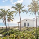 Ocean waves gently lapping a sandy beach with a small, charming house.